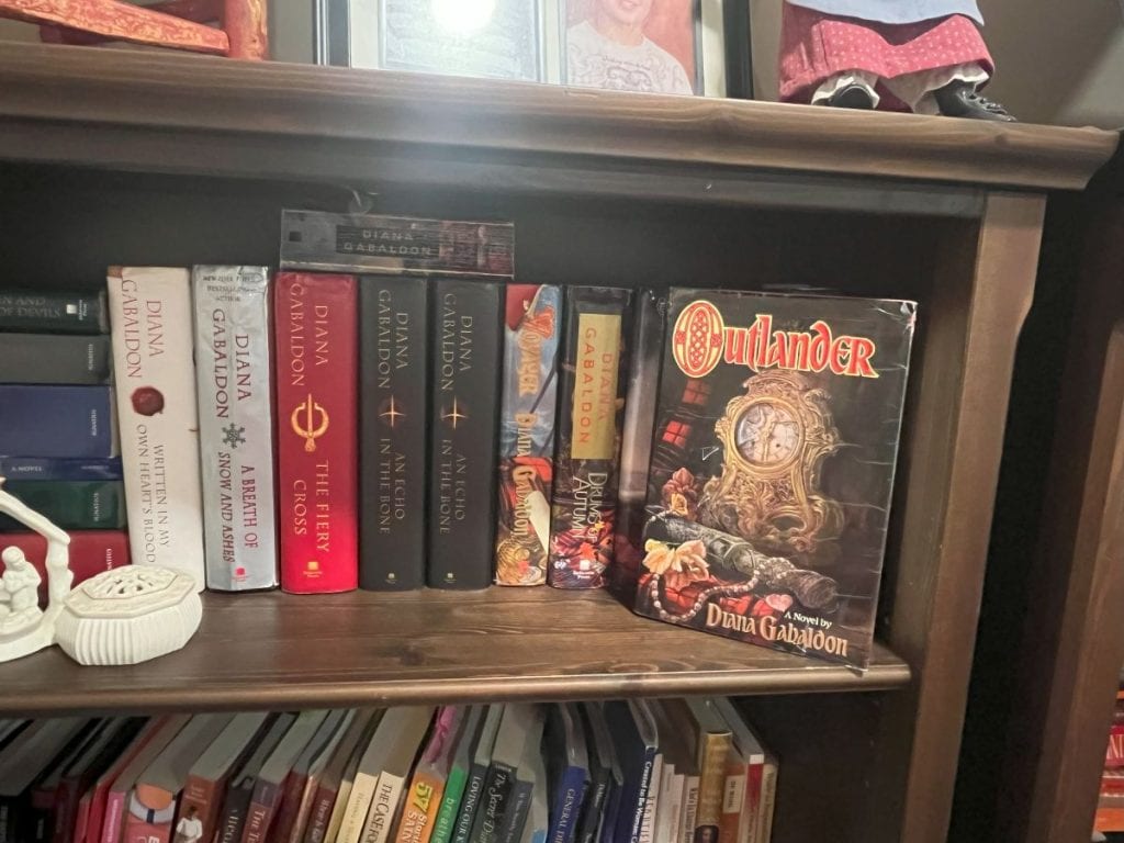 Diana Gabaldon book collection on bookshelf featuring Outlander novel in focus.