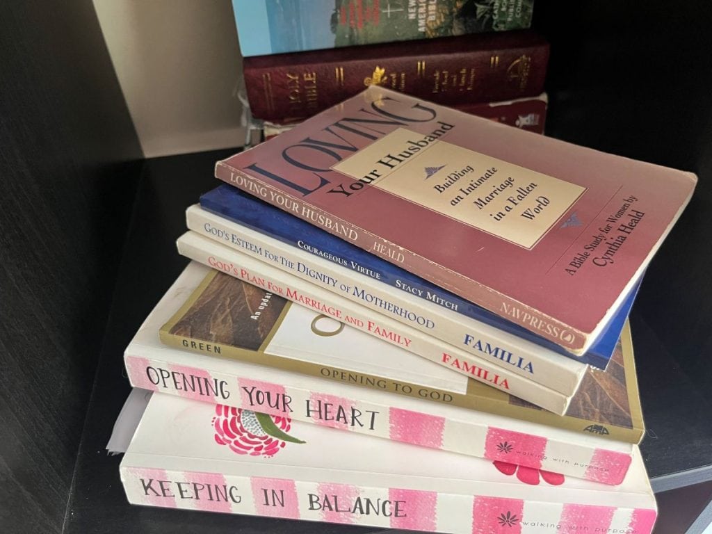 stack of bible study books including loving your husband, familia books and walking with purpose books. 