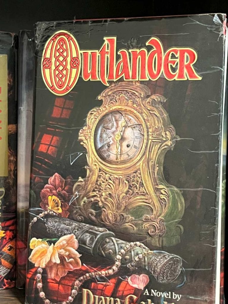 Hardcover book Outlander with picgure of a clock and red and black plaid and pearls
